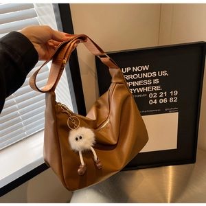 Détail d'un grand sac hobo marron en cuir texturé avec un joli pendentif en peluche