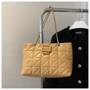 Close-up of khaki quilted tote bag featuring gold-tone chain strap and square buckle detail