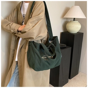 Detail of dark green corduroy tote bag showing textured fabric and fashionly print