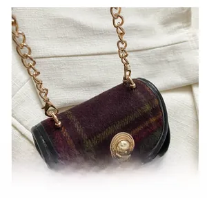Detailed close-up of retro plaid wool fabric and golden buckle on mini crossbody bag
