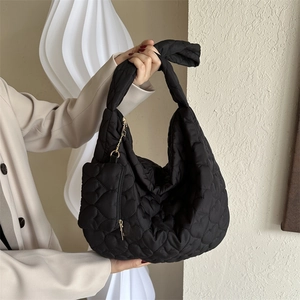Detail of black heart-quilted hobo bag with matching heart coin purse and knot handle