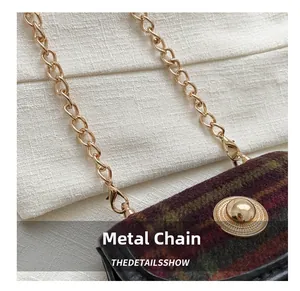 Detail of vintage plaid tweed texture with gold chain strap and metal buckle hardware