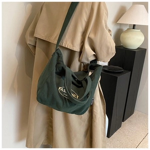 Detailed macro shot of dark green corduroy tote bag featuring white fashion embroidery