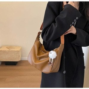 Détail du sac hobo marron texture litchi avec breloque petit monstre en peluche