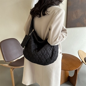 Close-up of heart-shaped quilting and small matching pouch on black tote bag
