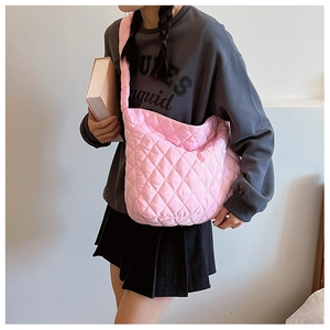 Sac hobo matelassé rose avec large bandoulière porté par un mannequin en gros plan