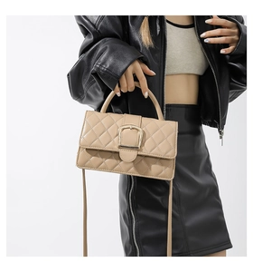 Détail du sac matelassé beige avec boucle fer à cheval dorée et poignée élégante