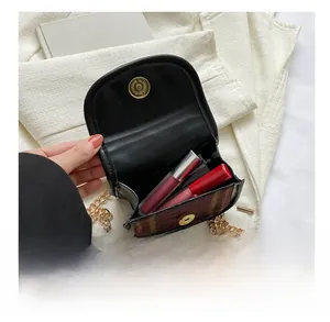 Detail view of mini plaid crossbody bag showing interior capacity for two lipsticks