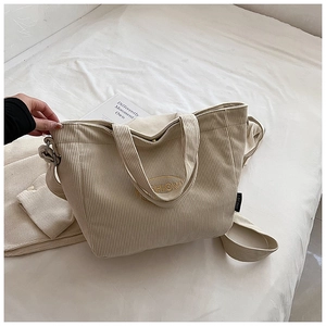 Detailed close-up of soft beige corduroy tote bag featuring SHION circular embroidery