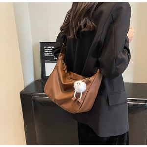 Détail du sac hobo en similicuir marron foncé avec un pendentif poupée en peluche blanche