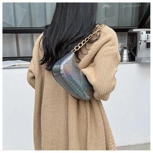 Chic silver holographic shoulder bag with gold chain strap shown in a lifestyle street setting