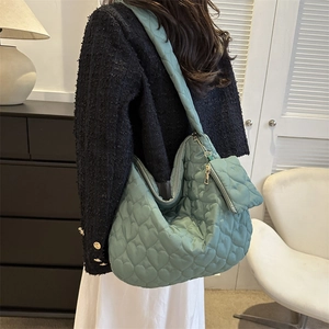 Detailed view of mint green quilted tote bag featuring heart patterns and small coin purse