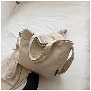 Detail of off-white corduroy tote bag showing textured fabric and fashion embroidery