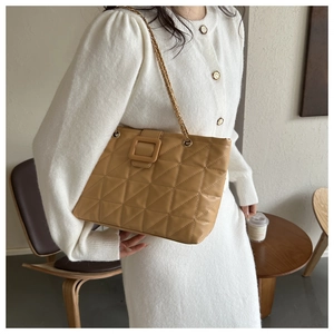 Close-up of khaki quilted tote bag featuring diamond pattern and metal chain strap