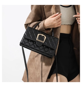 Détail du sac bandoulière matelassé noir avec boucle dorée et cuir texturé brillant