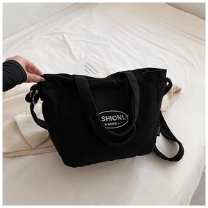 Detail of black corduroy tote bag showing fashionly embroidery and soft ribbed fabric texture