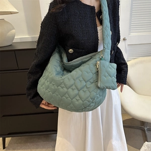 Detail of mint green quilted tote bag set with heart stitching and matching purse charm