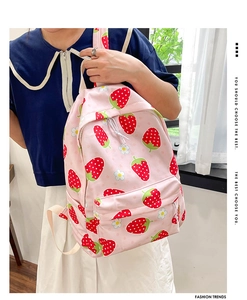 Detail of pink backpack featuring strawberry floral print and side carrying view