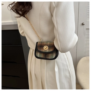 Close-up of retro plaid wool handbag with golden metal lock and chain strap on shoulder