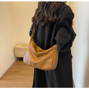 Sac hobo marron chic en cuir grainé porté par un mannequin avec un tailleur noir