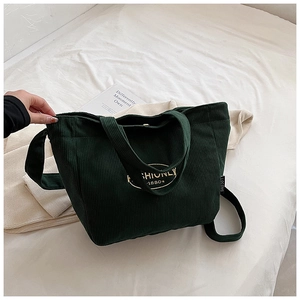 Detailed texture of dark green corduroy tote bag with golden FASHIONLY 1980 print