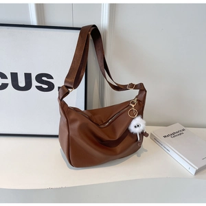 Détail du sac marron à motif litchi avec large bandoulière et pendentif en peluche