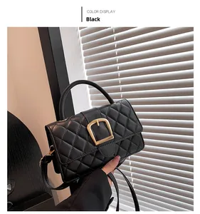 Détail d'un sac bandoulière noir matelassé avec boucle en fer à cheval dorée et poignée