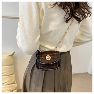 Detail of red and green plaid mini bag with gold metal lock and elegant chain strap