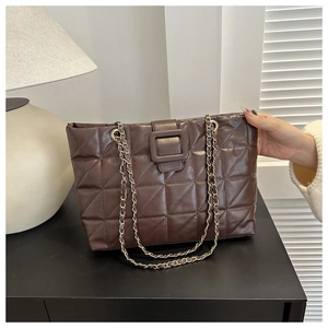 Detail of deep brown quilted tote bag featuring gold chain strap and polished leather texture