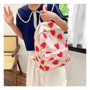 Pink school backpack with strawberry patterns and floral prints in a lifestyle setting