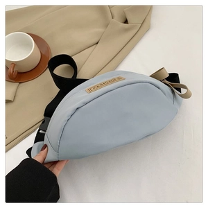 Dettaglio del marsupio in nylon azzurro con patch fashion e tracolla regolabile