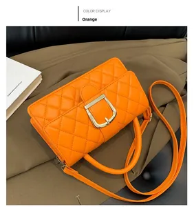 Détail du sac à main matelassé orange avec boucle dorée en D et finition en similicuir