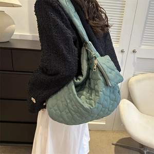 Detail of sage green heart-quilted puffer tote bag with matching mini heart coin pouch
