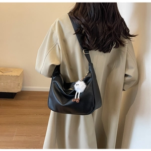Détail du sac hobo croissant noir avec accessoire de poupée en peluche tendance