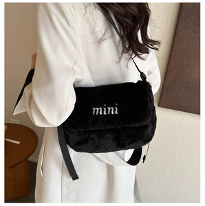 Détail du sac bandoulière en peluche noire avec broderie mini blanche sur la bandoulière