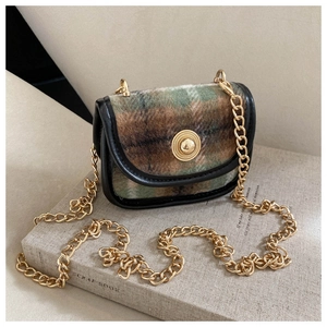 Close-up of retro plaid wool bag with gold chain strap and vintage circular button