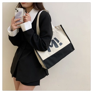 Détail du sac cabas en toile bicolore avec base noire et imprimé lettre M en gras