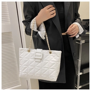 Detail view of white quilted tote bag featuring a gold chain strap and large buckle