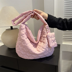 Detail of pink heart-quilted tote bag featuring gold zipper and mini pouch attachment