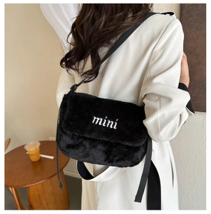 Détail du sac bandoulière en peluche noire avec broderie mini blanche et texture douce