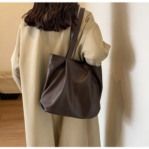 Detail of dark brown tote bag showing premium lychee grain texture and soft folds