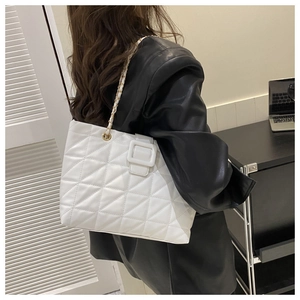 Close-up of white quilted tote bag with chain strap and square buckle on model
