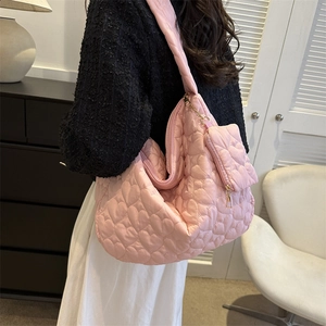 Detail view of pink quilted tote bag with heart embroidery and detachable heart-shaped pouch