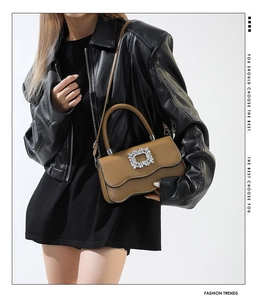 Détail du sac en cuir camel avec rabat ondulé et boucle en cristal sur robe noire chic