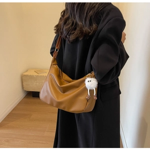 Vue détaillée du sac hobo en cuir marron avec un joli porte-clés monstre en peluche