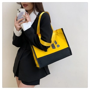 Détail du sac cabas en toile jaune avec imprimé lettres noires et large bandoulière
