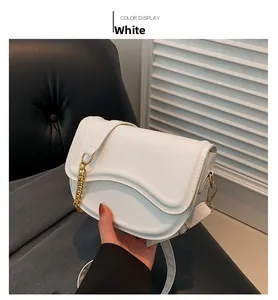 Detail of white PU leather saddle bag featuring a wavy flap edge and gold chain strap