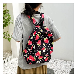 Outdoor view of a black backpack featuring red strawberry patterns and white polka dots