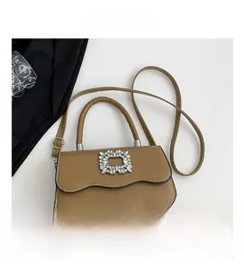 Détail du sac bandoulière marron avec bordure festonnée et boucle en cristal carrée