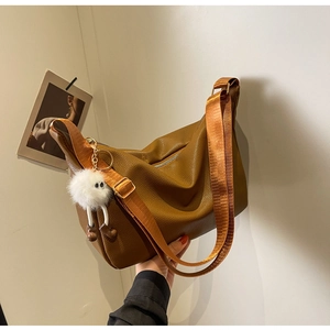 Détail du sac hobo marron foncé avec cuir texturé et large bandoulière tissée orange